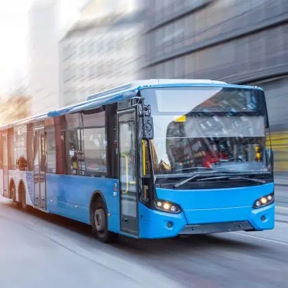 Blue bus moving on the road in city in early morning